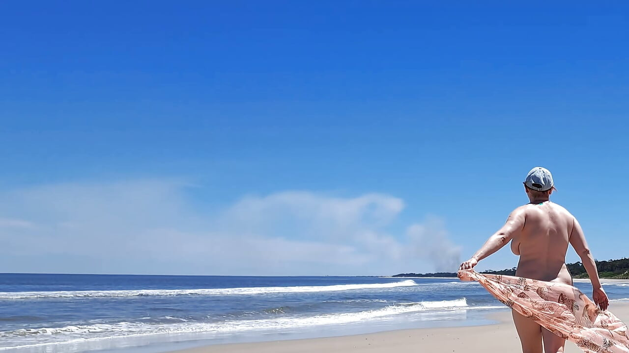 Amateur filming. A nudist plays with waves on the ocean shore.