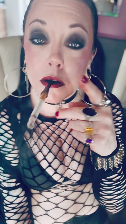 Fată gotică Tina Snua În cozi fumează o țigară într-un suport și se aprinde cu meciuri