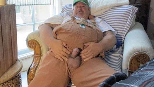 Спецодежда в нагруднике у дедушки-фермера с широкими ступнями без рук в комнате