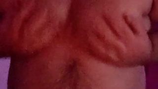 Une grosse chatte poilue joue avec ses seins, son ventre et sa bite