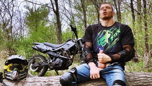 Przystojny rowerzysta podczas jazdy motocyklem w lesie szarpie się i spuszcza publicznie