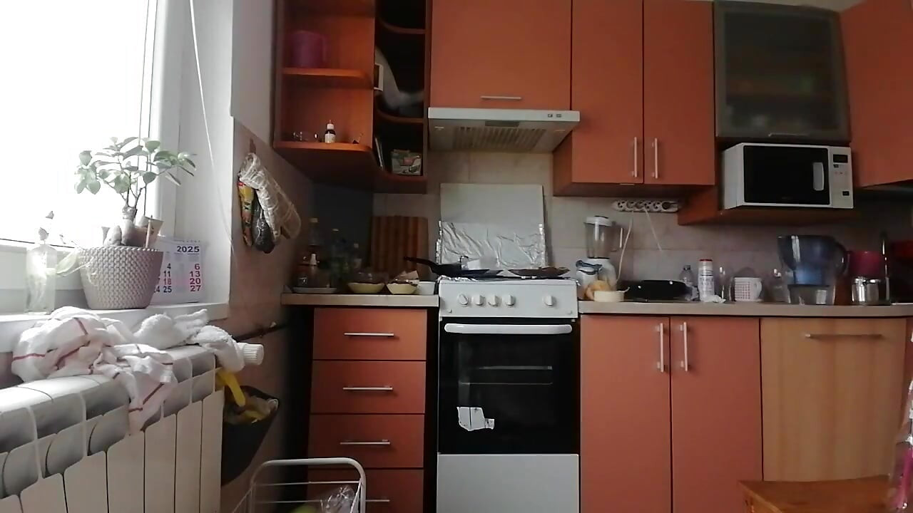 En sexig naken kvinna förbereder mat i köket