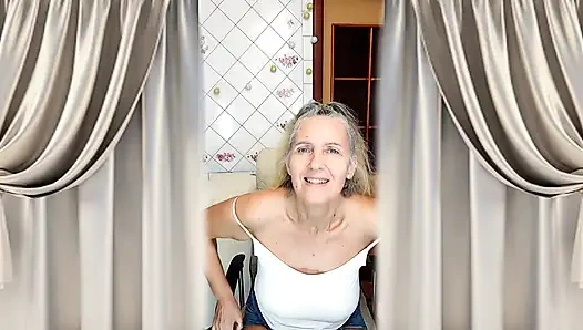 Reife großmutter mit grauen haaren, figur und füßen in der küche
