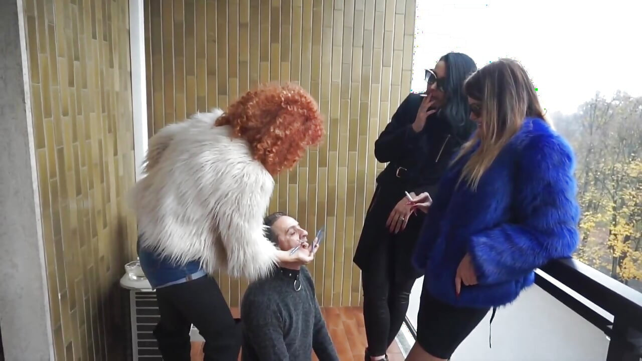 Fur-clad Femdoms Dominate Submissive on Balcony