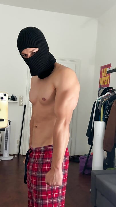 Young bodybuilder flexing his muscles in front of the mirror