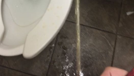 Pissend over het hele openbare toilet, zonder broek aan