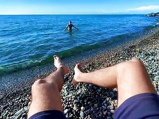 Un mec branle une bite sur une plage nudiste et un passant l’a rejoint