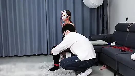 Seorang pacar muda, cantik, ramping, dan menggemaskan, dengan stoking hitam, tali merah, dan tali pengikat