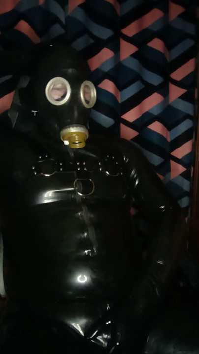 A guy in rubber pulls on a gas mask