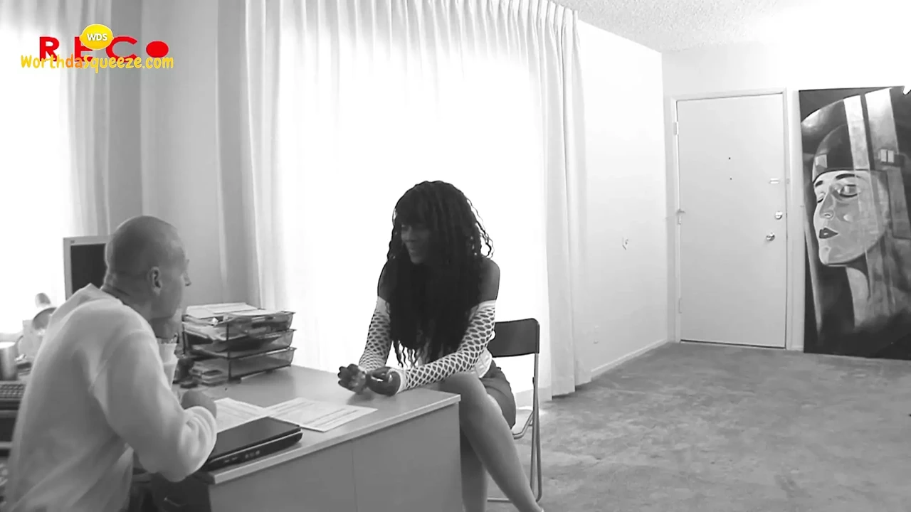 Slim ebony comes to office and kneels on desk