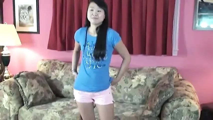 Asian broad with tattoos poses nude on the couch