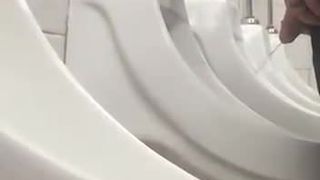 Macho circuncidado haciendo pis en el urinario