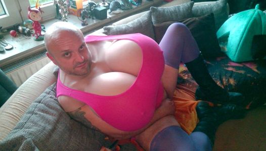 Enorme z-cup tieten travestiet in een fetisj-outfit met laarzen masseert en kneedt zijn grote borsten. Extreem grote xl borsten in roze