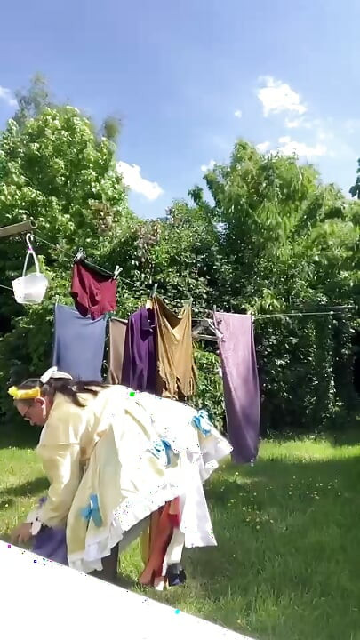 In an outfit with a yellow and blue maid dress to hang the laundry.