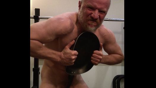 Strong muscle stud performs feat of strength bending a frying pan and jerks off