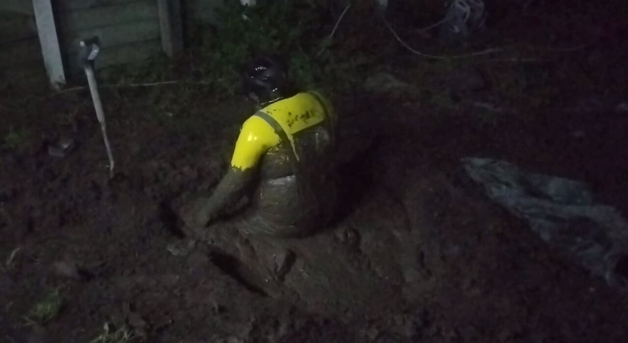 Latex Biohazard Drone Plays in Mud Pit
