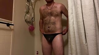 Un mec se douche dans un string noir et caresse une bite