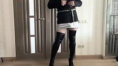 Sissy cuckold crossdresser in satin jacket, silk mini dress, high heels overknee boots dancing and playing with a cock