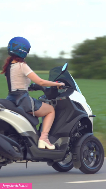 Jeny Smith rides a motorcycle in a short skirt.