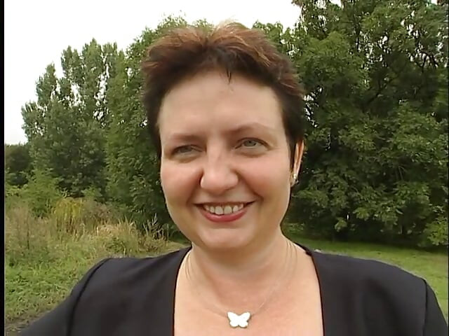 Une charmante femme mature suce la bite d'un mec dehors près de la voiture