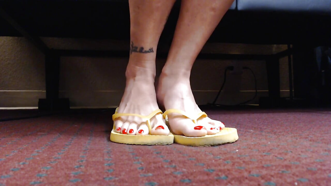 Κόκκινα νύχια κουνώντας κίτρινα σαγιονάρες