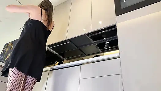 Heiße sexy brünette ehefrau mit langen beinen in schwarzen und roten netzstrümpfen mit einem satin-nachthemd neckt in der küche