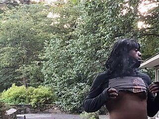 Ebenholz-Transvestit genießt draußen einen Rauch und strippt