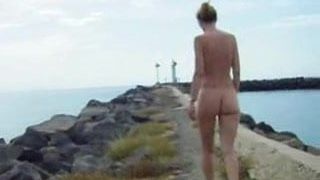 Festes Titten-Mädchen macht einen nackten Spaziergang am Meer.