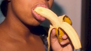 Шаловливая чернокожая с сексуальными губами играет с бананом