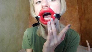 Zoomen in rote Lippen, offener Mundknebel für Dildo-Blowjob.