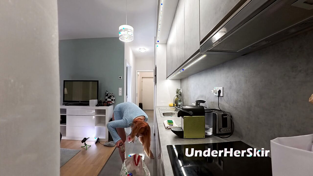 Het storbröstad underbart vacker rödhårig i köket med en kofta och stringtrosa visar sin skönhet och långa ben