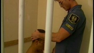 Prisioneiro está atrás das grades enquanto sopra o pau do oficial