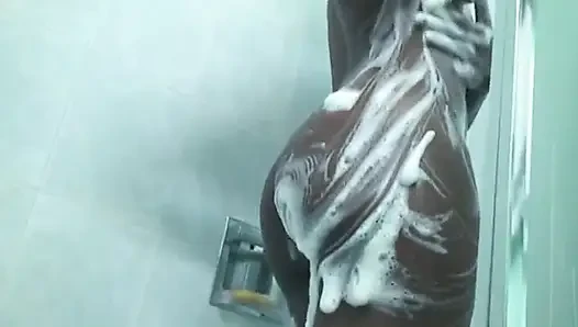 Langbeiniges schwarzes küken mit großen brüsten wird nass und seifig in der dusche im hotel