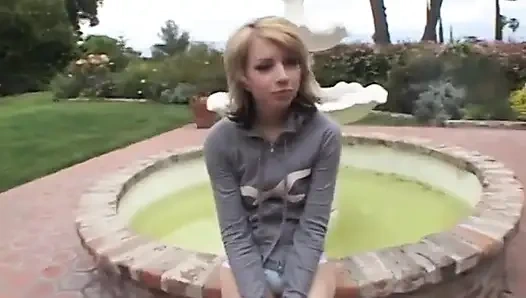 Skinny blonde naked slut sits on a couch while sucking on 2 BBC's