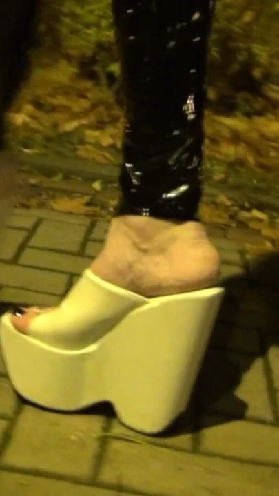 crossdresser walks on the street in latex leggings and very high white wedges | Clip 1