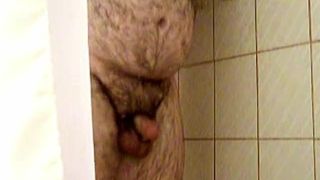 Harige mollige beer streelt zijn pik onder de douche