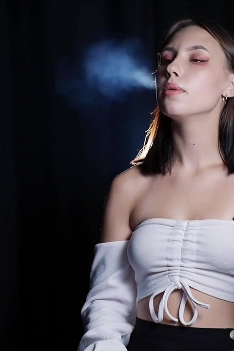 Si cewek elegan rambut cokelat lagi asik merokok di dark studio