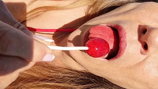 Melissa Johnson sucks and licks a cherry lollipop on the .beach