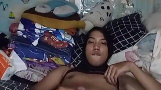 Une femboy sexy en hijab en bikini joue avec une bite sur le lit