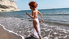 Сексуальная рыжая девушка наслаждается прогулкой у моря