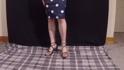 Transvestite in sexy black sandals and scuba dress tease