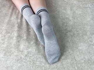 Girl in bed strokes her legs in gray cotton socks