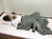 A college girl masturbates with her hand in her pants on the bed.