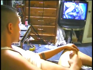 Latino in wifebeater watches TV as he jerks his meat