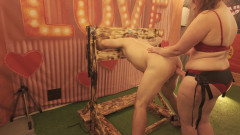 BDSM Mistress Pegging her slave in the stocks with a huge strapon