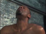 Two horny black men suck dick by a cement wall.