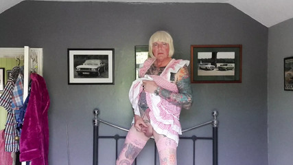 Angela with a tiny cock pissing on her bed dressed in her pink sissy dress